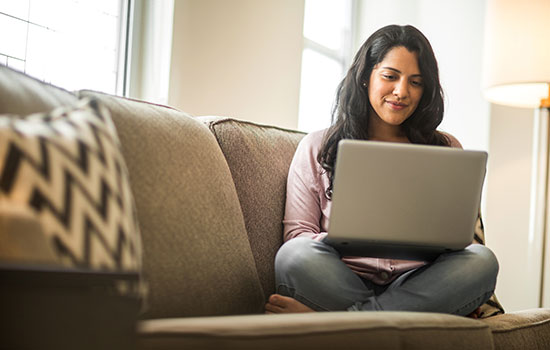 woman sitting cross-legged on a couch using a laptop