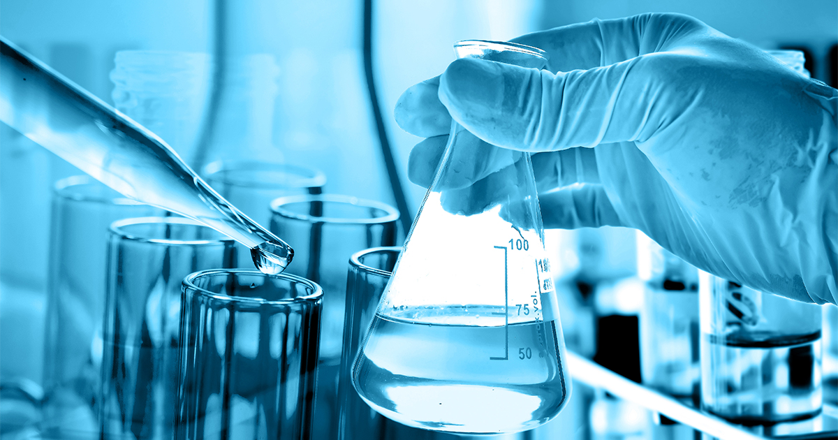 flask in a scientist's hand with lab glassware in the background